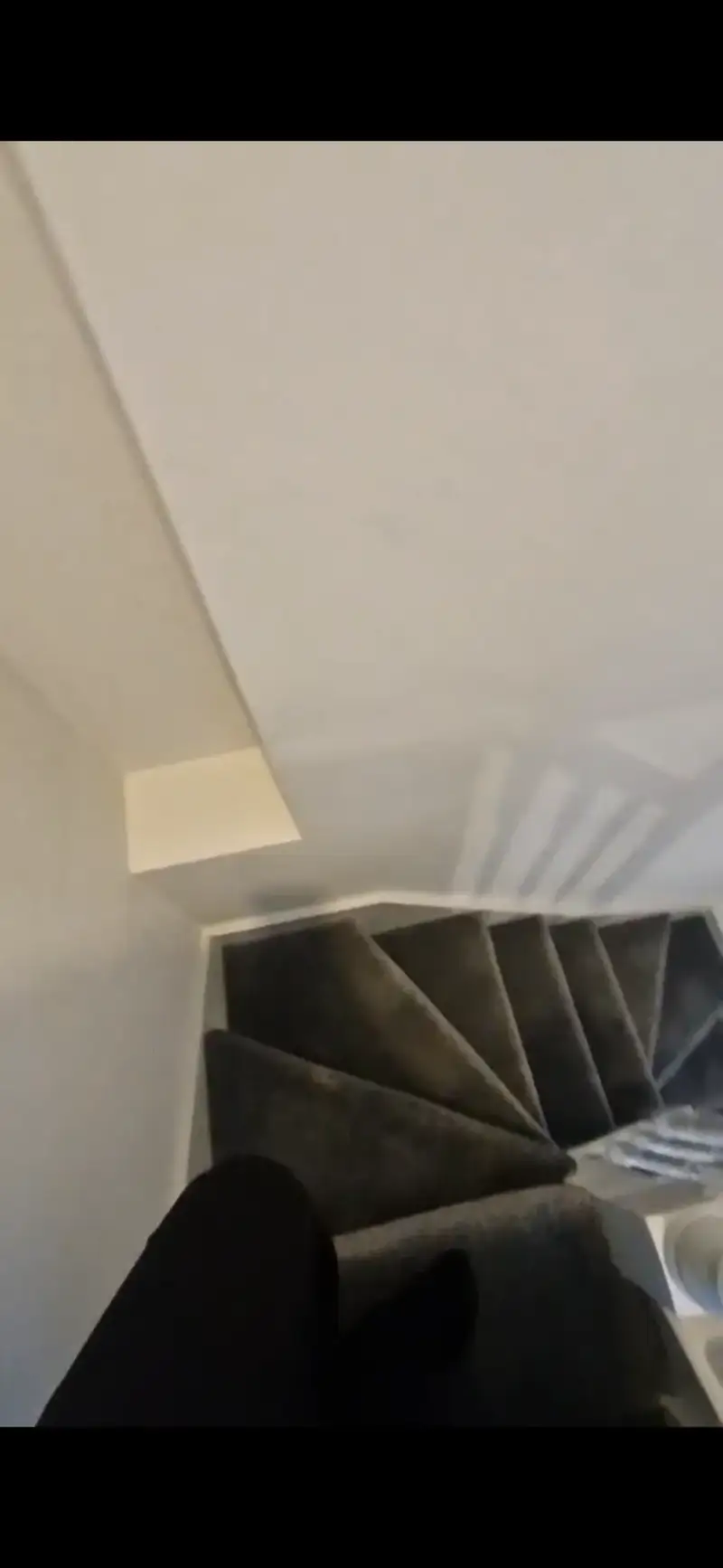 View down a narrow, carpeted staircase with white walls taken from the top landing.