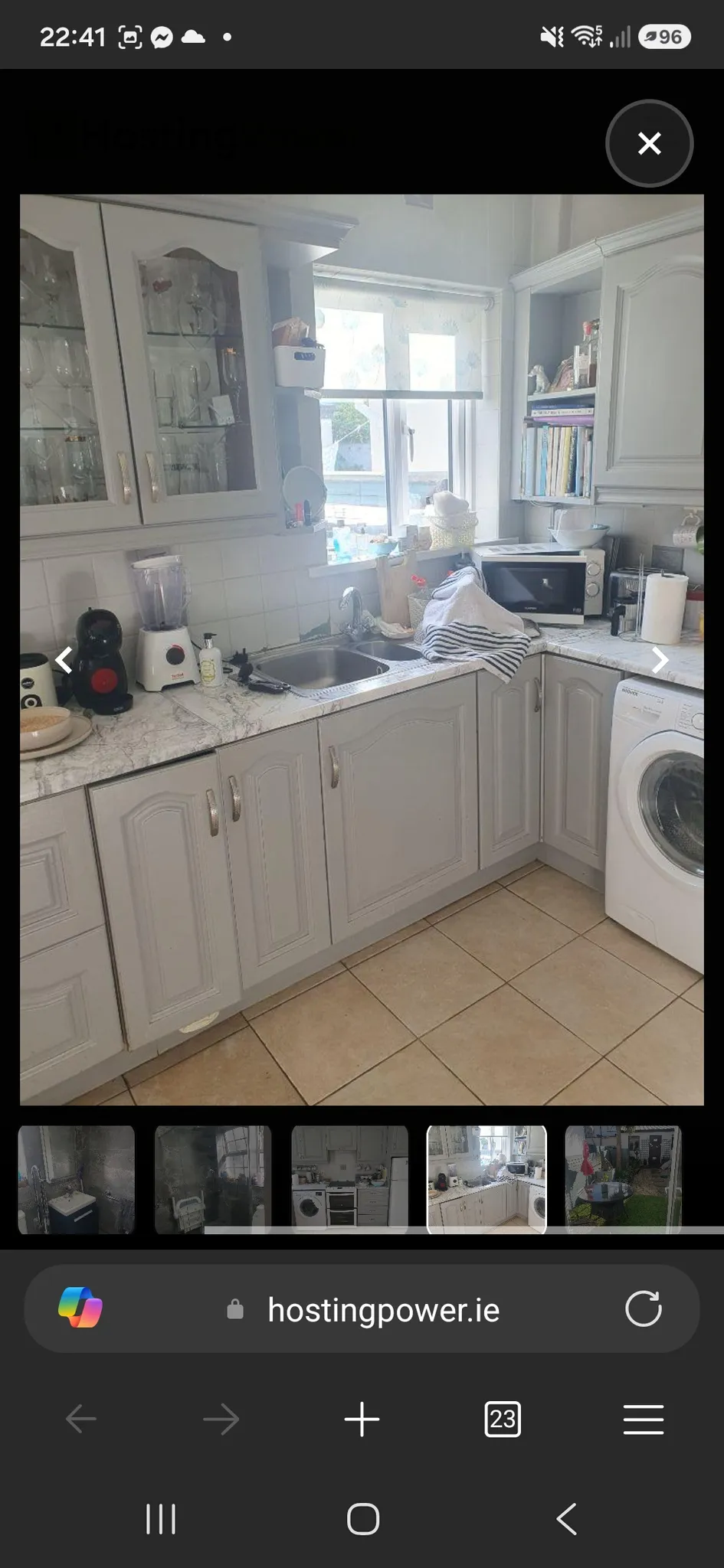 Kitchen with a sink under a window, upper and lower cabinets, countertop appliances and a washing machine