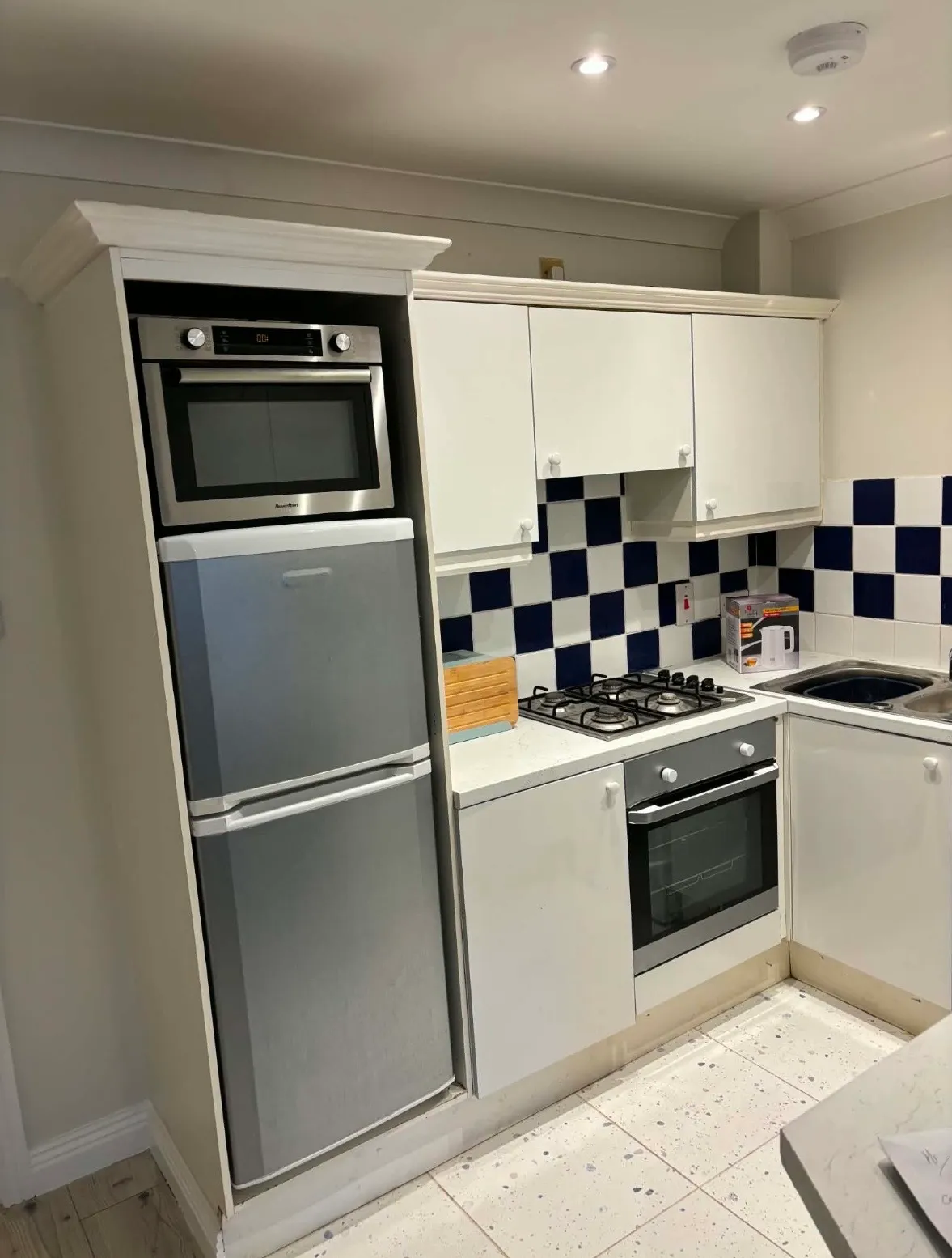 Kitchen with a built-in oven, refrigerator, gas cooktop, white cabinets and blue-and-white tiled backsplash