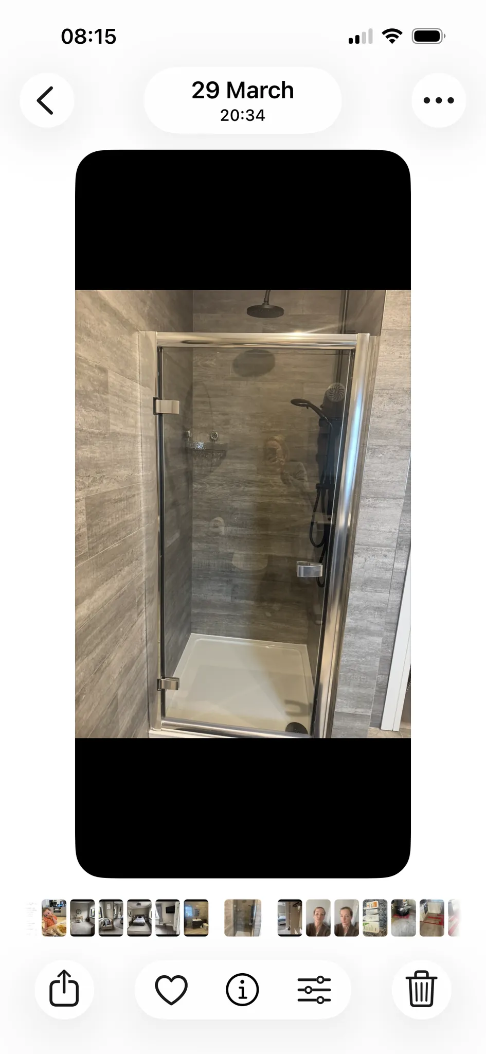 Bathroom shower with a glass door, grey tiled walls, overhead rain shower and a handheld showerhead.